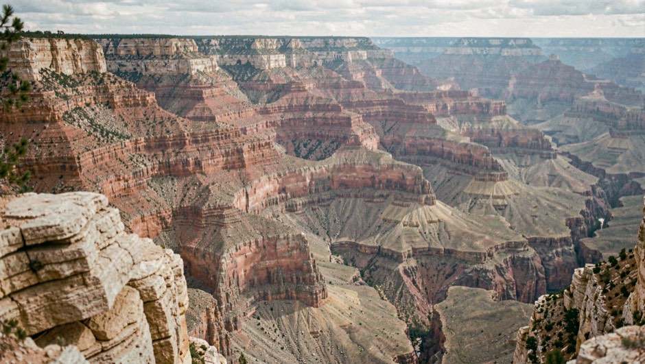 Grand canyon aux strates de grès superposées, la moitié gauche encore dans l'ombre bleue et la droite éclairée par le soleil levant